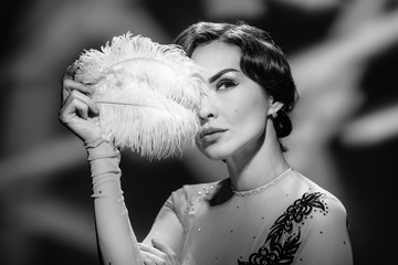 Beautiful elegant hollywood woman in vintage dress holding white feather