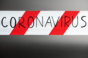 Label coronavirus. Red and white warning tape with the inscription coronavirus close up on black...