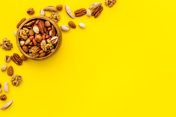 Mixed nuts in bowl - healthy snack - on yellow background top-down frame copy space