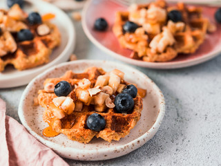 Easy healthy gluten free oat waffles with copy space. Appetizing homemade waffles with oat flour decorated blueberries, on plates over light gray cement background