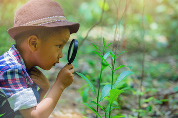 Happy little boy with magnifying glass explorer and learning the nature at home backyard