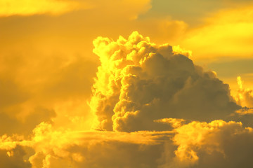 bright orange yellow sunset light in dim sky with fluffy clouds