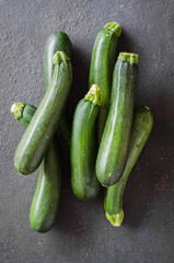 Freshly harvested zucchini, green vegetables on dark background.