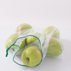 Zero waste, plastic free recycled textile produce bag for carrying fruit apples or vegetables, a white surface. Reusable using. Copy space.