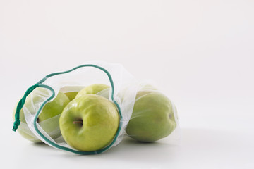 Zero waste, plastic free recycled textile produce bag for carrying fruit apples or vegetables, a white surface. Reusable using. Copy space.