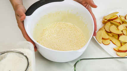 Cake dough in a bowl close up on white background. Step by step Apple pie recipe.