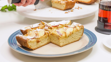 Slices of fresh baked Apple pie close up on a plate on white kitchen table. Woman serving cake