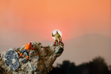 Miniature people: Hikers climbing up on the rock . Sport and leisure concept.