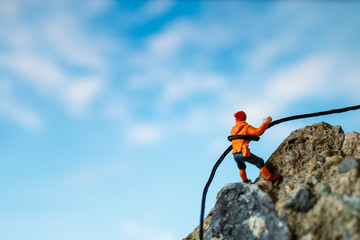 Miniature people: Hikers climbing up on the rock . Sport and leisure concept.