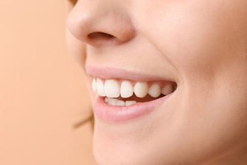 Young woman with healthy teeth on color background, closeup