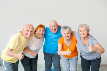 Happy elderly people showing thumb-up gesture in gym