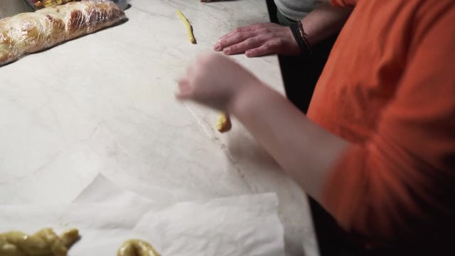 Mother and child preparing cookies at home, push out shot of kid rolling dough