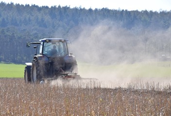Bauer pflügt mit Traktor ein Feld in großer Hitze
