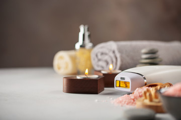 Modern laser photo epilator with bath accessories on light background. Home Spa salon. Stay at Home. Beauty concept of quarantine.