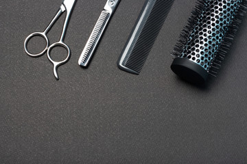 Hairdressing scissors and comb on a black background, copy space