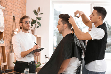 Young man with professional hairdresser and model during courses in salon