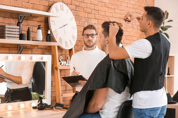 Young man with professional hairdresser and model during courses in salon