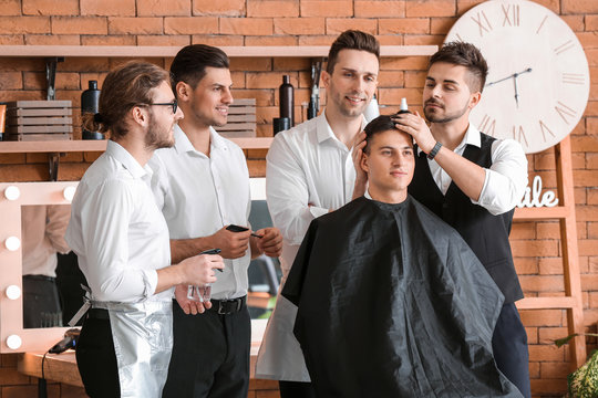 Professional hairdresser teaching young men in salon