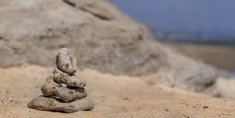 Fototapeta na wymiar Zen concept. Object made of stone on the beach. Stone pyramid for meditation. Harmony and Meditation. Zen stones.