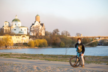 Portrait of a teenager in the sunset in a mask on a blue bicycle. Quarantine. It is forbidden to ride a bicycle. Covid-19.