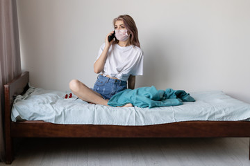Young woman in protective medical mask online, communicates by phone. stay home concept. Quarantine...