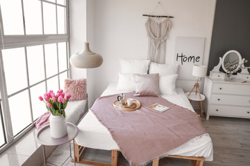 Interior of beautiful modern bedroom with spring flowers