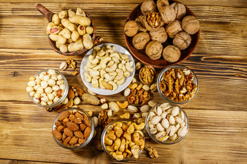 Obraz na płótnie Canvas Assortment of nuts on wooden table. Almond, hazelnut, pistachio, peanut, walnut and cashew in small bowls. Top view. Healthy eating concept