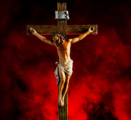 A small statue of Jesus Christ on the Cross with red smoke