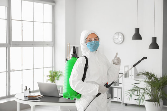 Worker in biohazard suit disinfecting office