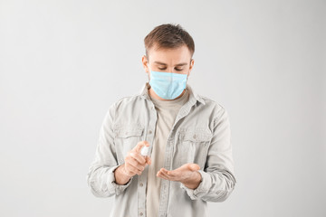 Man with disinfectant on grey background