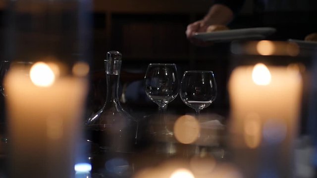 Candlelit Romantic Dinner Being Served By Waiter In Slow Motion With Out Of Focus Candles As Foreground 