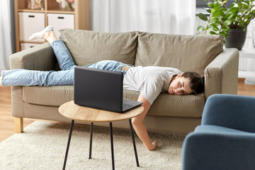 people, boredom and depression concept - bored or lazy young woman with laptop computer lying on...