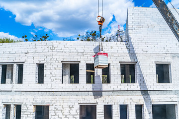 Construction crane in front of a multi storey building under construction lined with bricks.