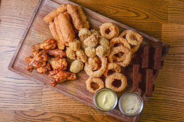 Delicious golden batter deep fried snacks, served on old dark wooden rustic board. Junk food, fast food concept.