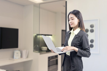 Asian businesswoman standing while using a laptop working from home