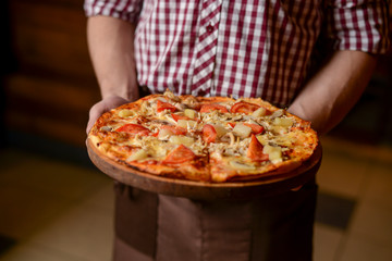 A waiter holds a plate of tasty food. Italian cuisine in restaurant, Delicious pizza with spinach, olives and mushrooms