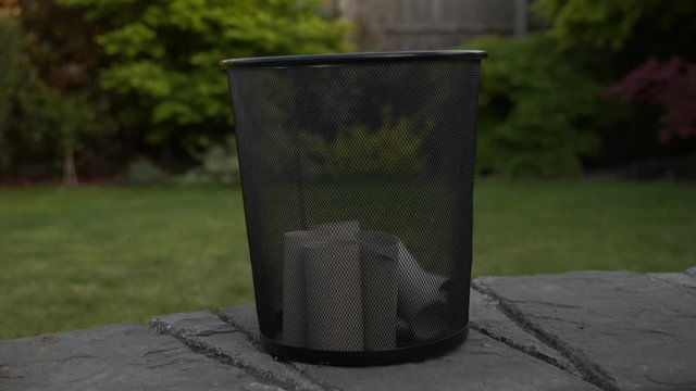 Side view of empty toilet paper rolls uniformly emptied into trash can, 180p to 30p slow-motion