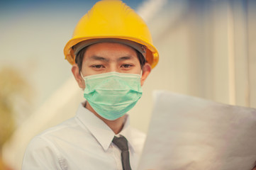 Fototapeta na wymiar Businessman holding paperwork planing blueprint and use surgical mask protect working on construction site