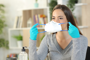 Woman with gloves putting mask avoiding coronavirus at home
