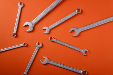 Steel wrenches on an orange background, top view