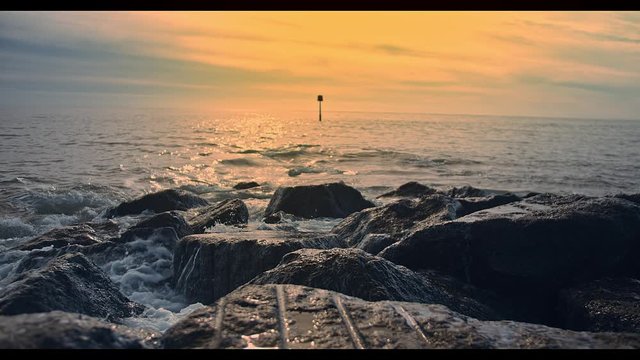 Sea waves crashing with splash on rocky shore. Big Rocks washed by the waves on dawn, dover kent, folkestone beack kent.