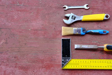 Tools on a red wooden background, square, keys, place for an inscription, top view