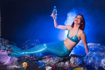 Fantasy stupid mermaid in deep ocean. Plastic trash and bottles pollution in ocean. Ecocatastrophe, garbage and plastic recycling concept.