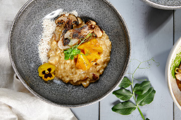 Risotto with white mushrooms and pumpkin in gray bowl