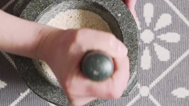Footage of woman pulverising Chios Mastic and Mahaleb in granite mortar, slow motion