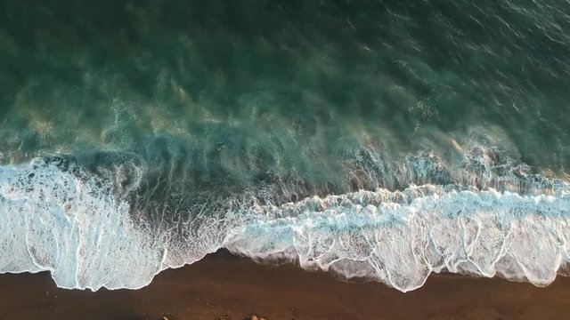 Aerial view of seawaves going to and fro on a seashore in a beach.