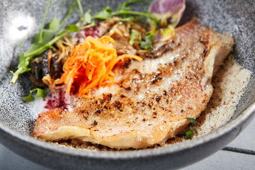Sea bass fillet with shiitake mushrooms in gray bowl top view