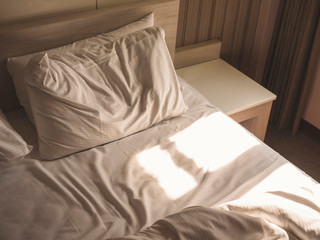 Bed Mattress and Pillows Mess up Bedroom with morning sunlight