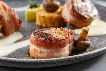 Pork in bacon with vegetables in vegetarian style