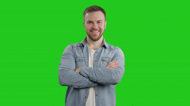 Young man crossed arms on green screen and smiling. Portrait of handsome guy posing with folded arms at chroma key. 4K, UHD